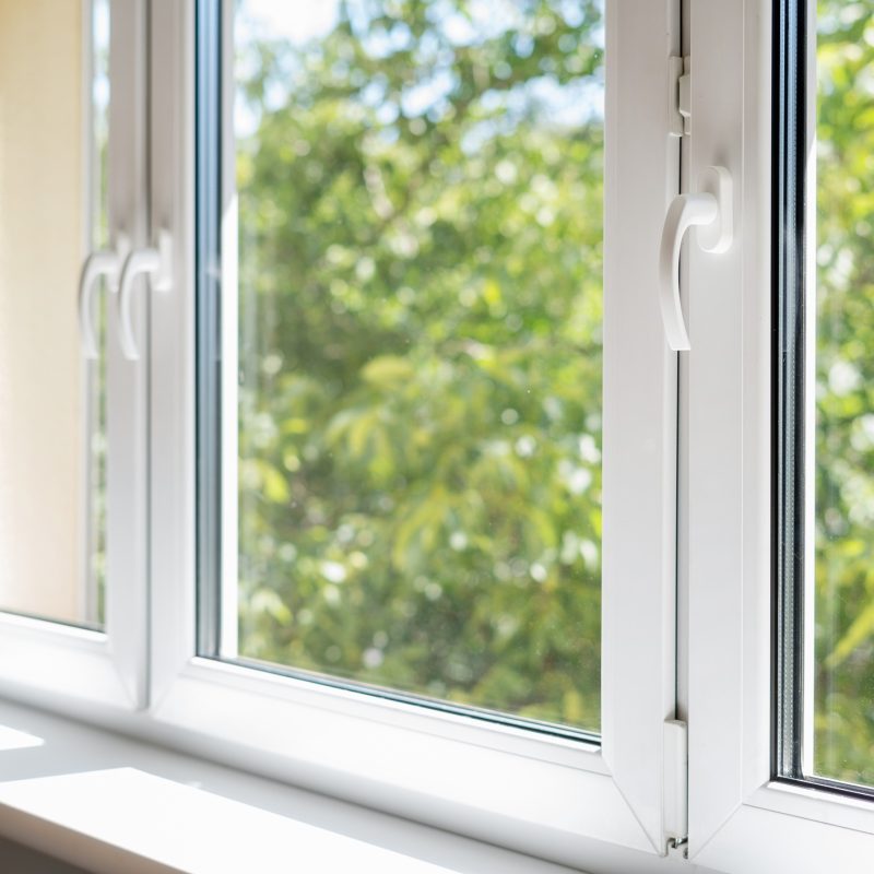 new plastic pvc window with white metal frame installed at modern house, view of blurred green trees. advertising concepts
